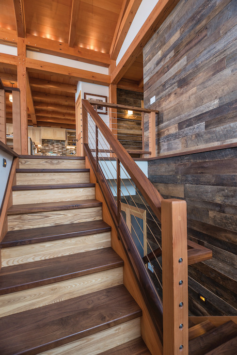 The custom staircase, crafted by NEWwoodworks, is made of walnut and ash, giving a two-toned appearance that complements the reclaimed wall paneling by Pioneer Millworks. The custom staircase, crafted by NEWwoodworks, is made of walnut and ash, giving a two-toned appearance that complements the reclaimed wall paneling by Pioneer Millworks.
