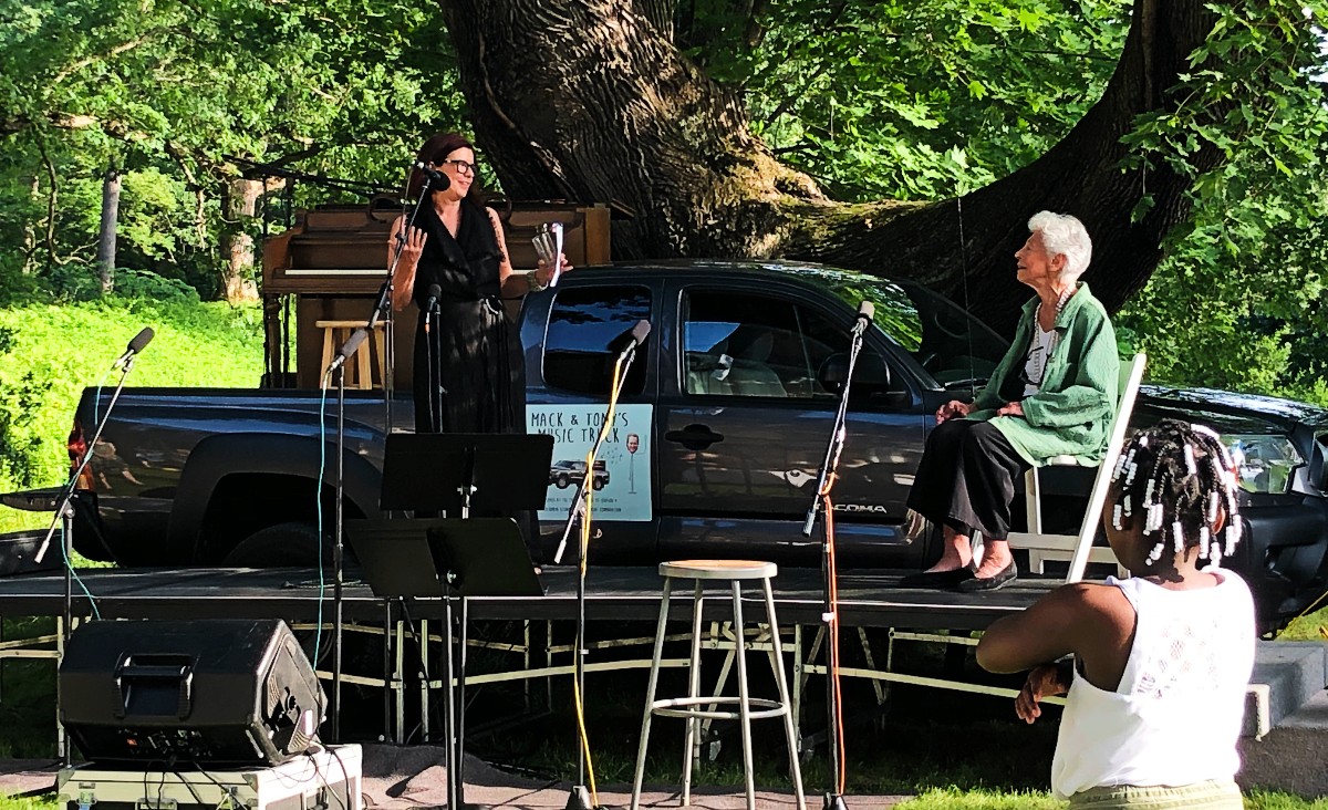 Susan Henrickson, president of the Hudson Hall Board of Directors, welcomes the guests as Joan Davidson looks on.