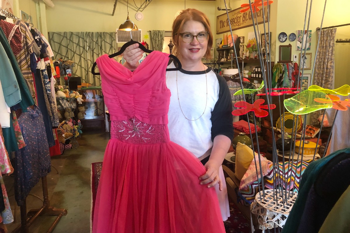 POSY owner Regina Moran holds up one of the vintage gowns for sale.