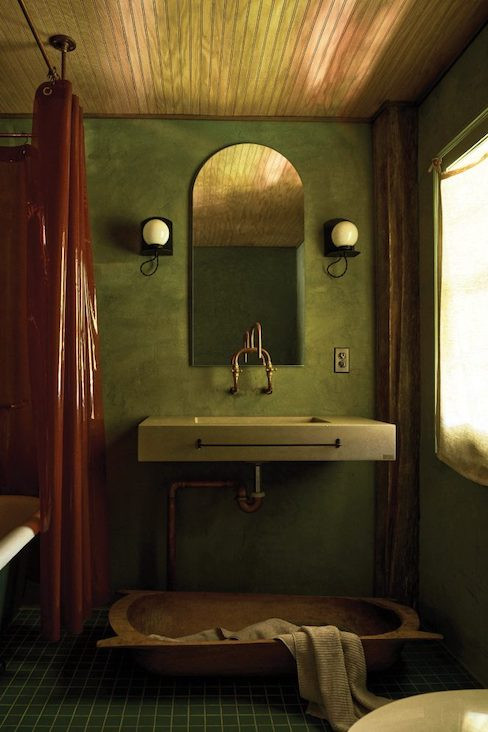 The first-floor bathroom has moss green concrete walls and deep green floor tiles.&nbsp;
